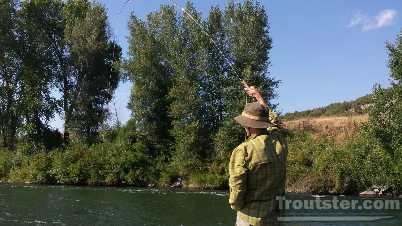 A fly fisherman fighting a large trout.